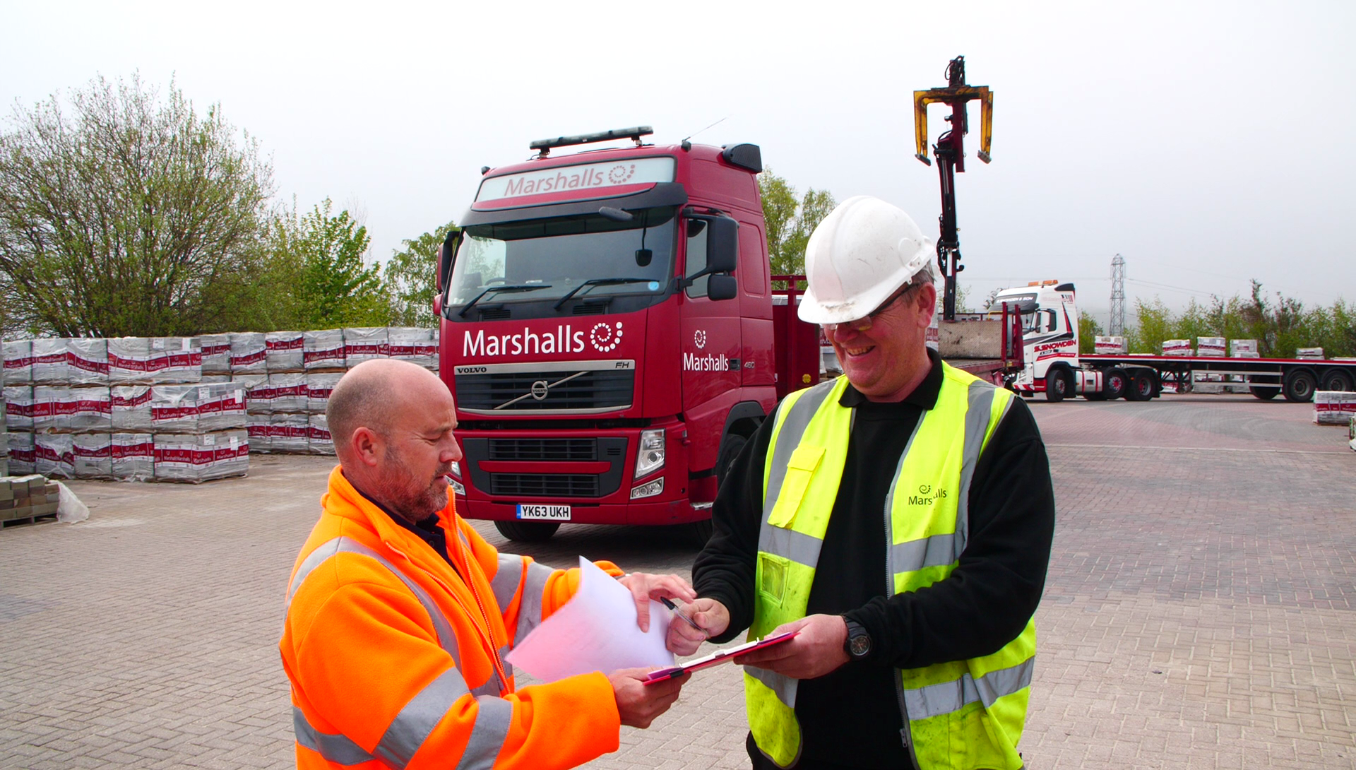 Marshalls staff signing delivery paperwork with a Marshalls lorry in a background