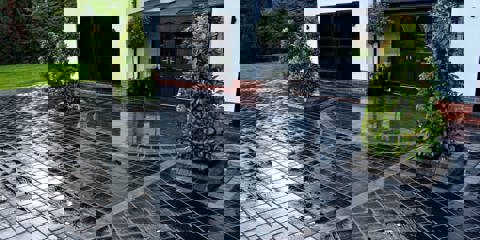 Marshalls Drivesys Riven paving laid on a driveway with three green trees near the entrance of the house