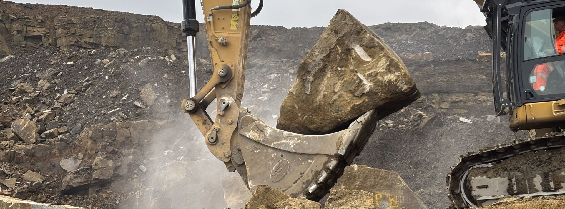 An excavator picking up a block of stone