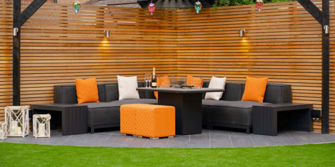Marshalls Symphony Planks paving in a modern garden with dark grey garden furniture and orange cushions