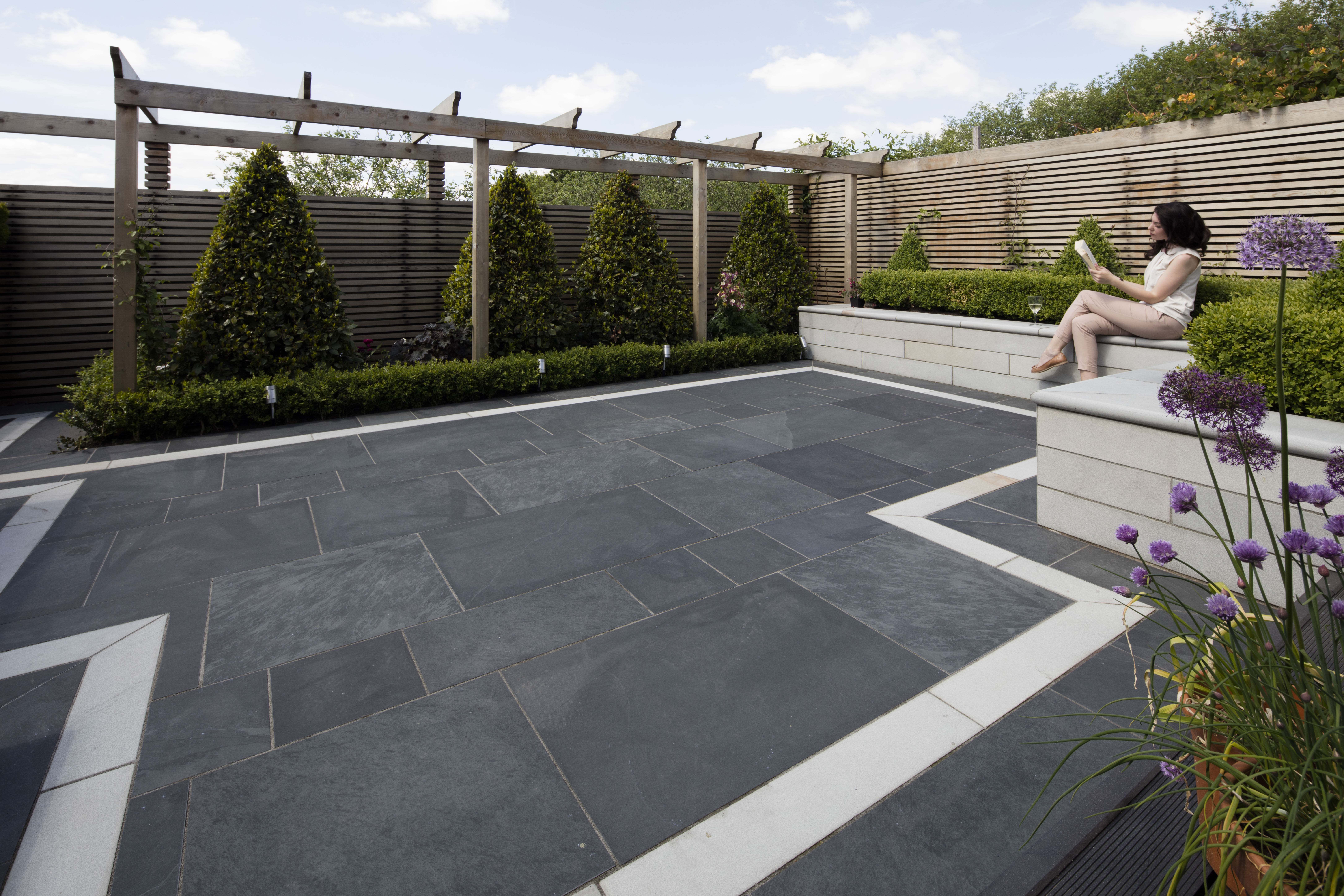SYMPHONY® Classic in Blue A lady reading and enjoying a glass of wine in a paved garden area