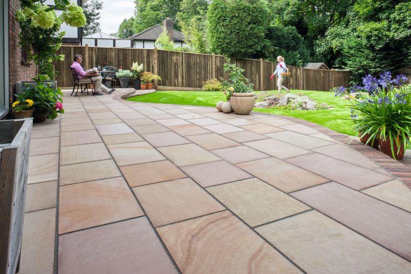 A simple garden with a buff patio and green lawn