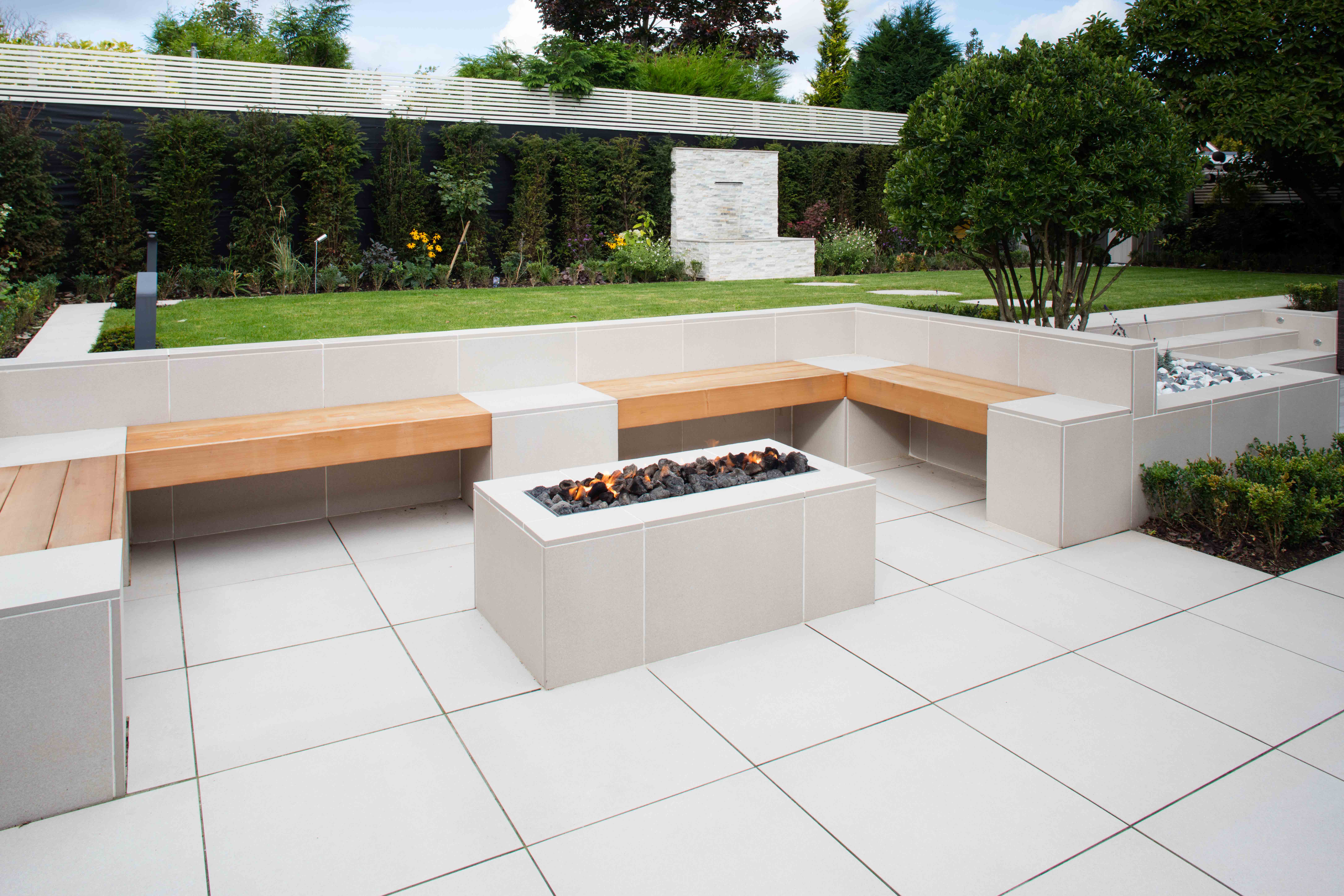 SYMPHONY® Classic in Barley A firepit in the middle of a light-coloured garden paving area