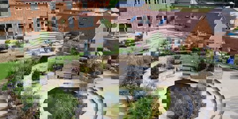 An aerial view of a garden with Marshalls Sawn Versuro paving and a circle feature with lots of greenery and wooden furniture