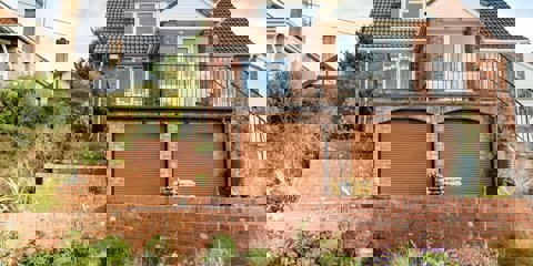 The front of a house with a multi level garden created using plants and Marshalls old mill bricks 