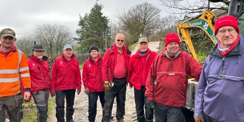 Staff in red waterproof jackets and black waterproof trousers