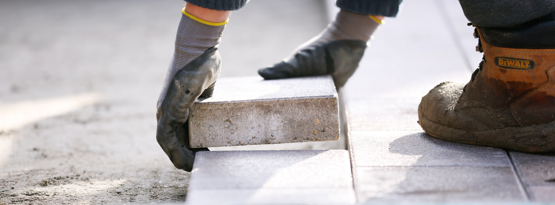 A landscaper laying blocks on a driveway