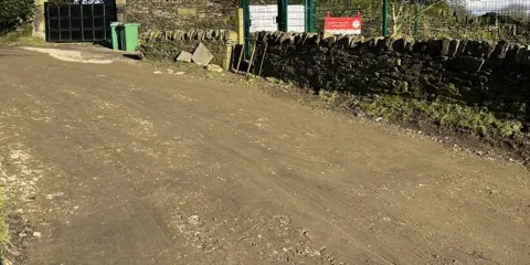 A muddy road with stone walls either side