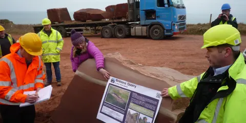 Staff on-site in high-vis workwear looking at a poster 